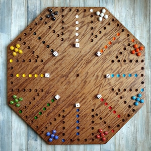 May include: A wooden board game with a unique octagonal shape. The board is stained a warm brown and features numerous holes for colored marbles. Dice and marbles in various colors, including yellow, green, blue, red, orange, black, and white, are scattered across the board.