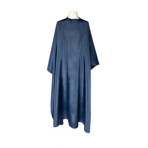 May include: A dark blue hair cutting cape with a simple design. The cape is made of a smooth, water-resistant material.