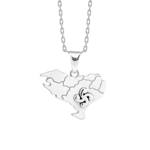 Puede incluir: Collar con colgante de plata con forma de mapa del País Vasco. El colgante tiene un contorno detallado y un diseño estilizado de la cruz vasca. La cadena es una delicada cadena de plata.