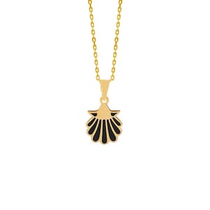 Op de afbeelding: Een goudkleurige ketting met een schelpenhanger. De hanger is zwart en goud, met een schelpenontwerp. De ketting is ook goudkleurig. De achtergrond is effen wit.