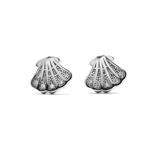 May include: A pair of silver earrings shaped like seashells with small clear gemstones.