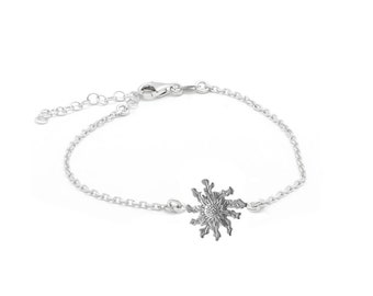 May include: A silver chain bracelet with a delicate flower charm. The flower charm is detailed and intricate, with a textured surface.