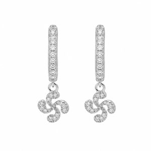 May include: A pair of silver-toned hoop earrings featuring a dangling charm shaped like a four-armed curved cross. Both the hoop and the charm are encrusted with small, clear, sparkling stones that cover the entire front surface of the jewelry.