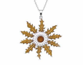 May include: A silver pendant necklace featuring a central white flower with a textured amber-colored center, surrounded by a ring of jagged, golden-brown leaves. The pendant hangs from a delicate silver chain against a plain white background.