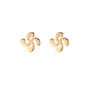 May include: A pair of gold-colored stud earrings. Each earring features a stylized, four-armed design with rounded edges, set against a white background. The earrings have a polished, reflective surface.