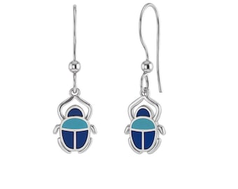 May include: A pair of silver-toned drop earrings featuring a beetle-shaped charm. Each charm is inlaid with dark blue and light blue enamel sections, suspended from a simple silver hook wire with a small spherical bead accent above the beetle.