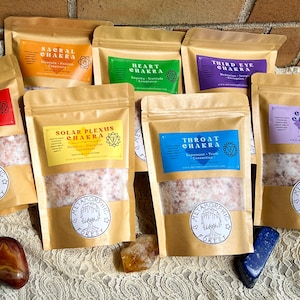 May include: Seven brown paper bags with different colored labels and text. Each bag contains a white powder and has a round sticker with a tree and the words "Metamorphic Forest". The labels have the names of the seven chakras: Root, Sacral, Solar Plexus, Heart, Throat, Third Eye, and Crown.