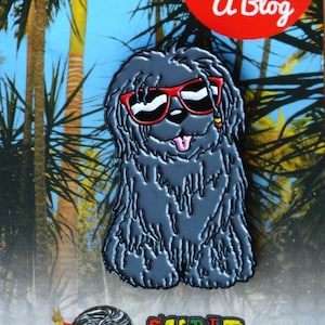 May include: Black and white enamel pin of a dog wearing sunglasses and a red bandana. The dog is sitting on a background of palm trees and a blue sky. The text "Dread Dog with A Blog" is in a red circle above the dog. The text "SUPER DREAD" is below the dog. The text "www.superdreadshop.com" is at the bottom of the image.