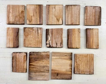 May include: A collection of fifteen rectangular wooden coasters. The coasters are made of natural wood with varying shades of brown and tan, showcasing the wood grain. They are arranged on a white surface.