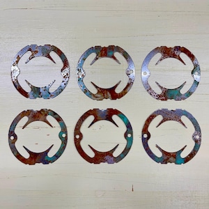 May include: Six circular metal objects with a distressed, rusted appearance. Each ring has a unique pattern of cutouts and holes, with hints of blue and green oxidation. The overall aesthetic suggests an industrial or vintage theme.