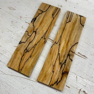 Puede incluir: Dos piezas de madera con un patrón de veta de madera natural único. La madera se ha quemado para crear un diseño oscuro e intrincado. La madera es de color marrón claro.