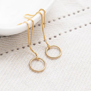 a pair of gold earrings sitting on top of a white plate