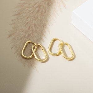 a pair of gold earrings sitting on top of a table