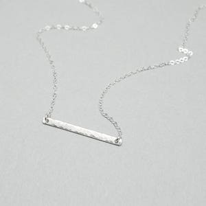a silver bar necklace on a silver chain