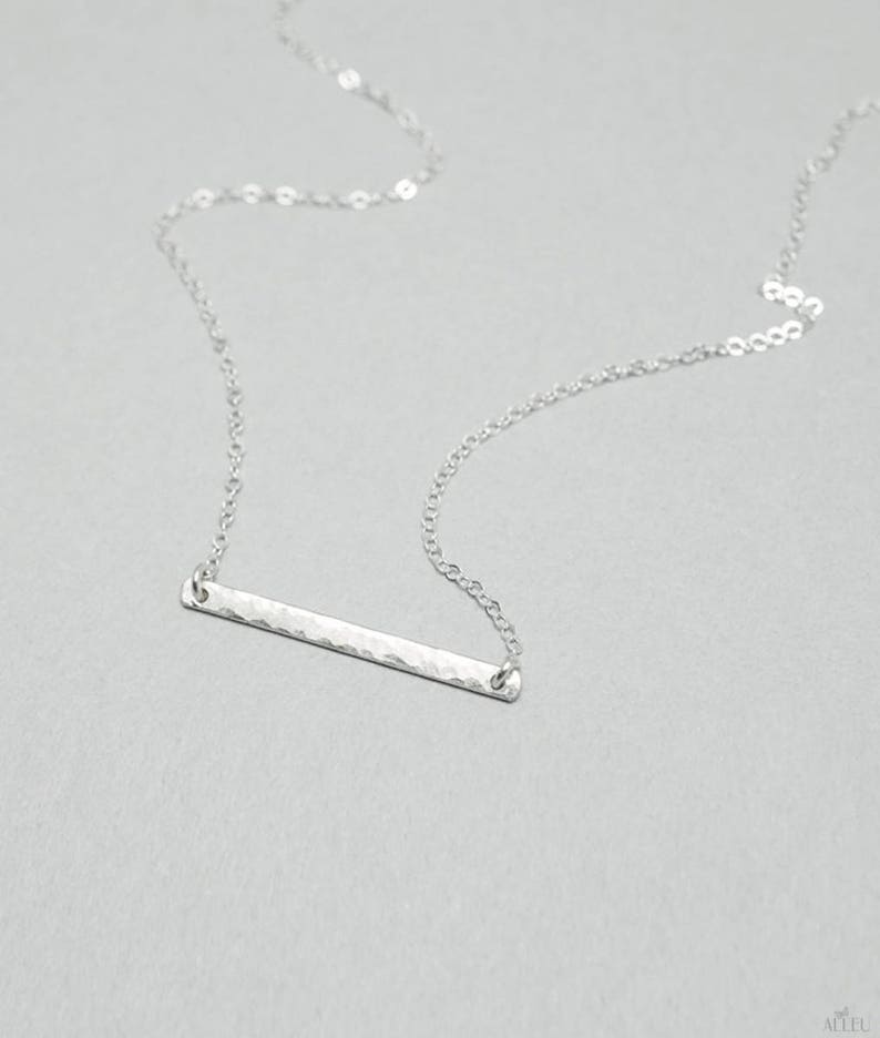 a silver bar necklace on a silver chain