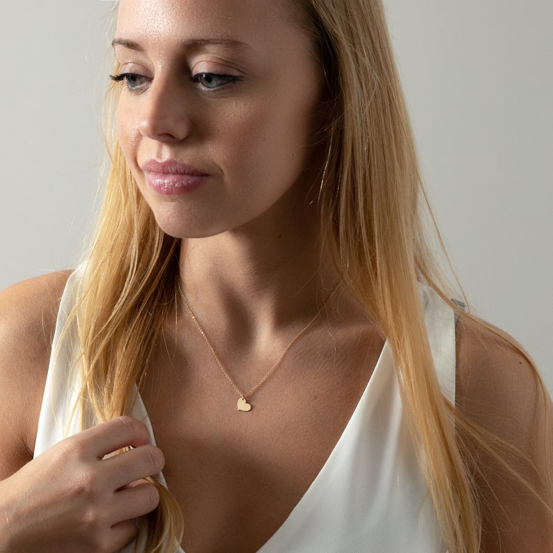 a woman in a white top is holding a necklace
