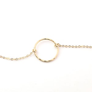 a gold bracelet with a circle on a chain
