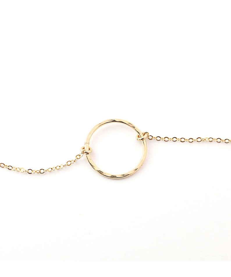 a gold bracelet with a circle on a chain