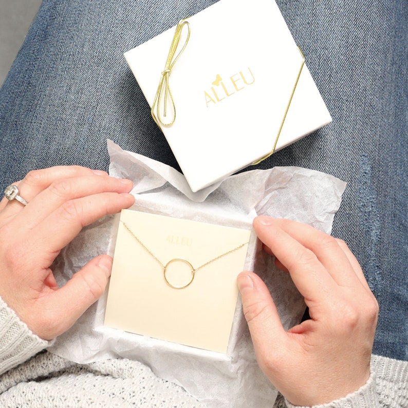 a woman holding a box with a necklace in it