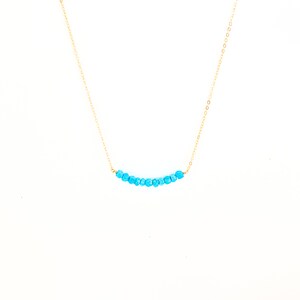 a blue beaded necklace on a gold chain