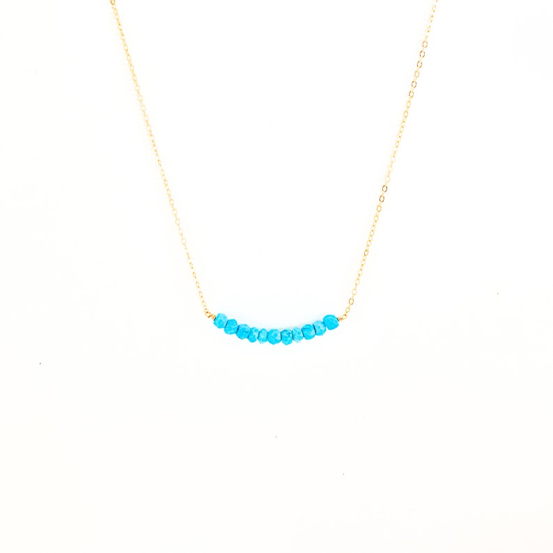 a blue beaded necklace on a gold chain