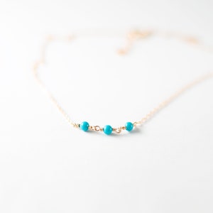 a gold chain with a turquoise bead on it