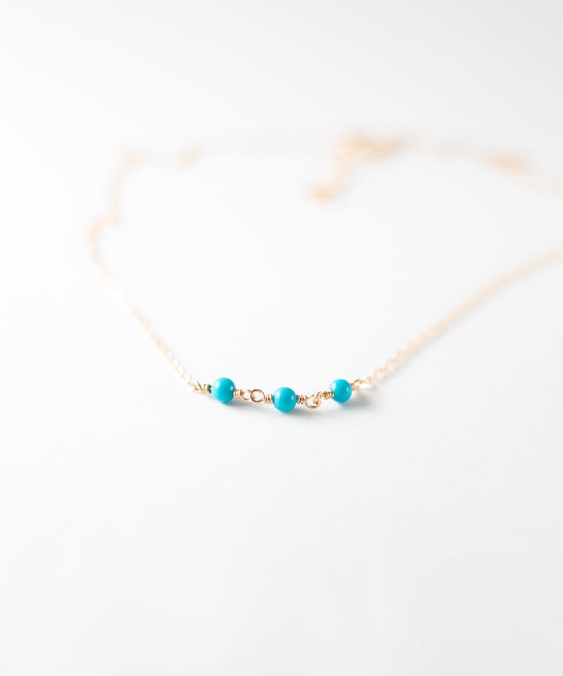 a gold chain with a turquoise bead on it