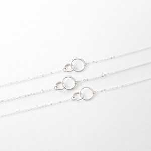 three silver necklaces on a white background