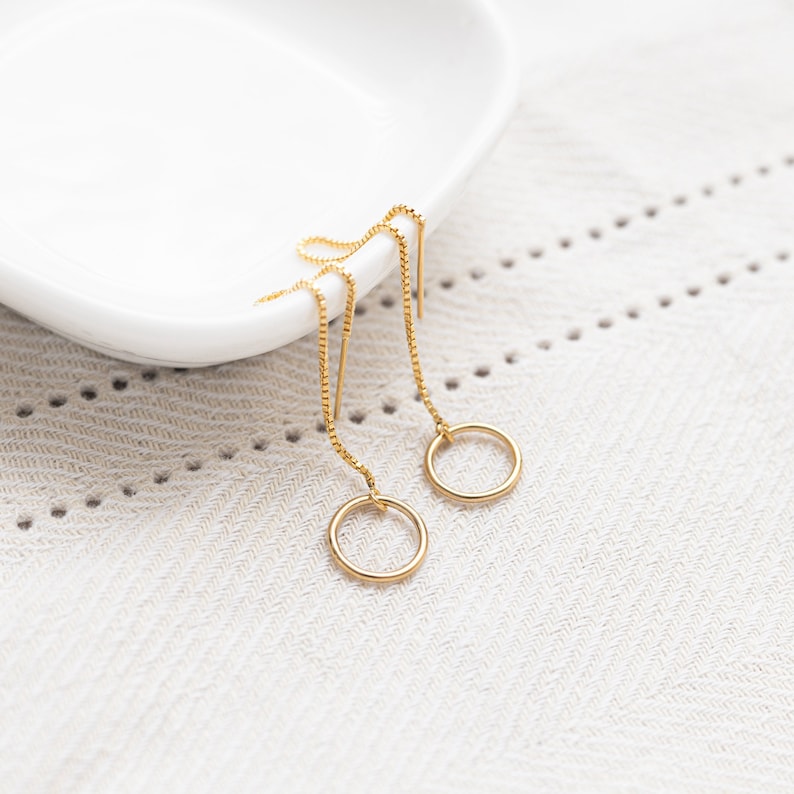 a pair of gold earrings sitting on top of a white plate