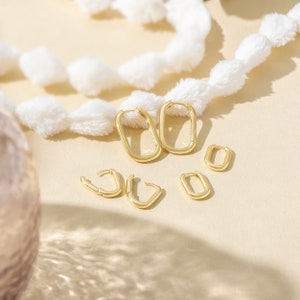 a pair of gold earrings sitting on top of a table