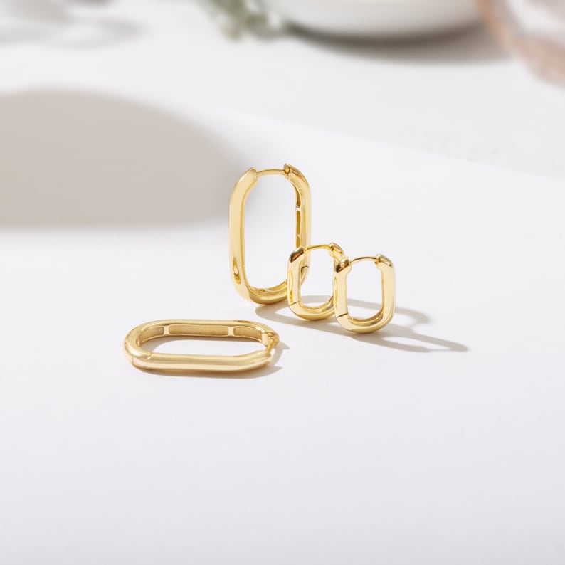 a pair of gold earrings sitting on top of a table