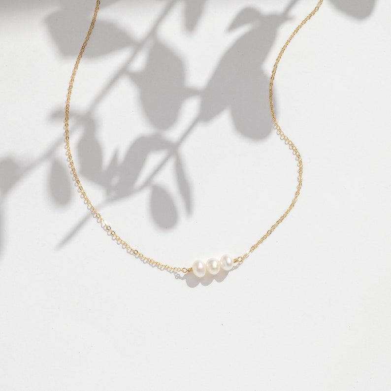 a necklace with three pearls hanging from it