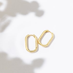 a pair of gold earrings sitting on top of a white surface