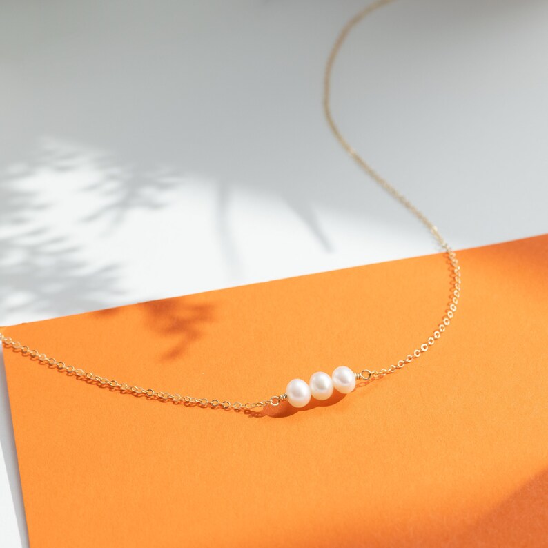 two pearls on a gold chain on an orange card