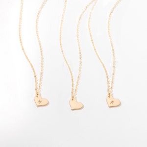 three gold heart necklaces on a white background