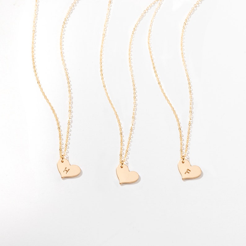 three gold heart necklaces on a white background