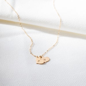 a gold necklace with two hearts hanging from it