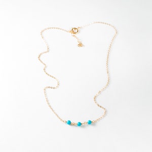 a gold chain with a turquoise beaded necklace
