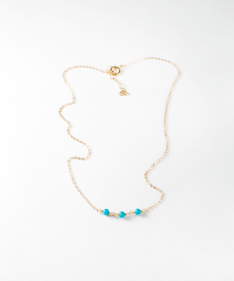 a gold chain with a turquoise beaded necklace