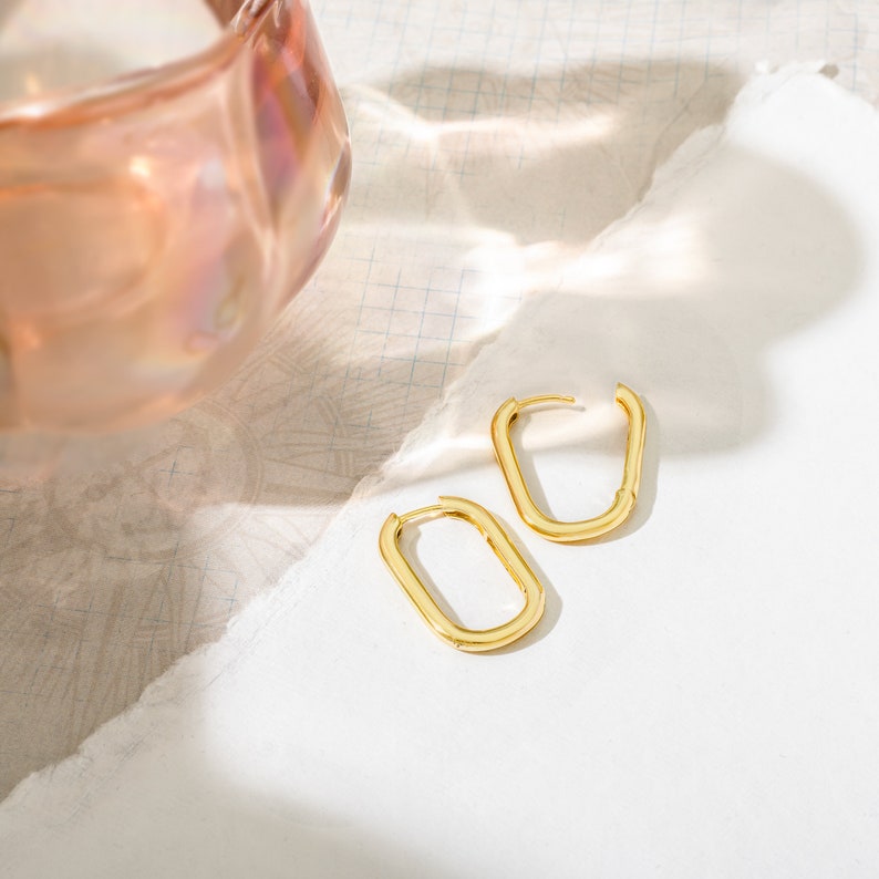 a pair of gold earrings sitting on top of a table