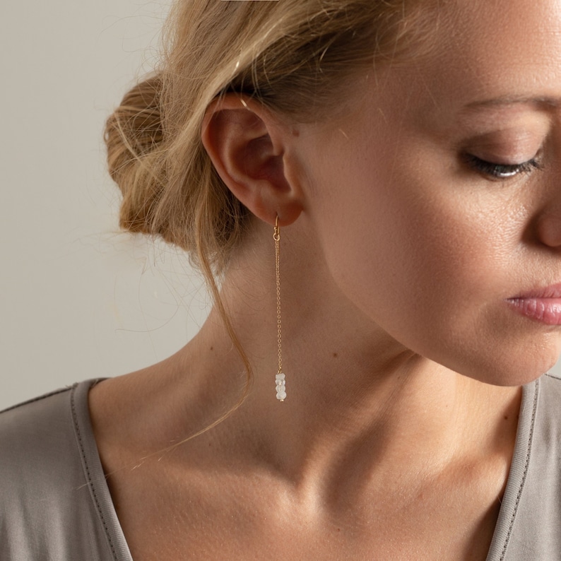 a woman wearing a pair of gold earrings