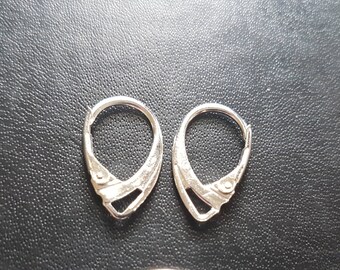 May include: Silver earring hooks, a common type of earring finding, are shown in a close-up image. The hooks are made of metal and have a simple design.