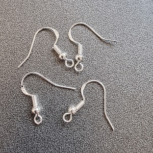 Puede incluir: Cuatro ganchos para pendientes de plata con una pequeña bola en el extremo de cada gancho.