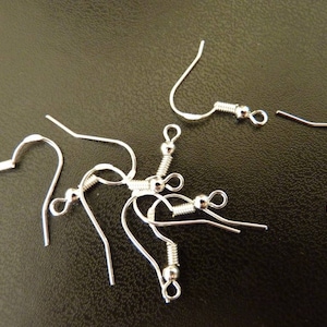 Puede incluir: Un juego de seis ganchos para pendientes de plata con una pequeña bola en el extremo de cada gancho.