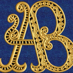 Puede incluir: Letras bordadas en oro "A" y "B" sobre un fondo de mezclilla azul.