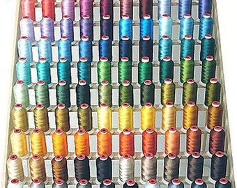 Op de afbeelding: Een houten rek met 100 spoelen garen in verschillende kleuren. De spoelen zijn gerangschikt in rijen en kolommen, en het rek is gemaakt van hout met een natuurlijke afwerking.