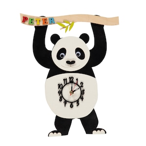 May include: A black and white panda bear clock hanging from a wooden branch with the name "PETER" spelled out in colourful letters. The clock face is white with black numbers and hands.