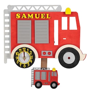 May include: A red fire engine shaped clock with a pendulum and a smaller fire engine at the bottom. The clock face has black numbers and yellow hands. The fire engine has the name "SAMUEL" written on the side.