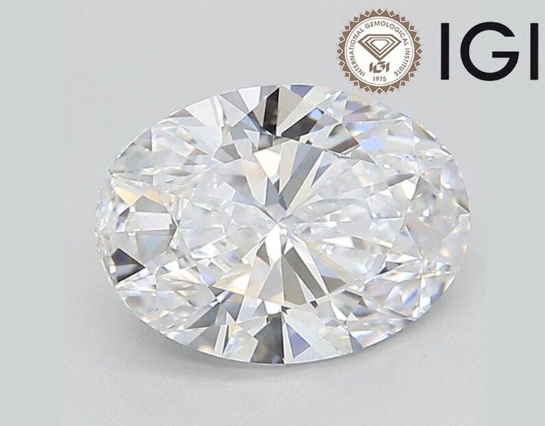 May include: A clear oval-shaped diamond with a brilliant cut. The diamond is set in a ring and is surrounded by a silver band.