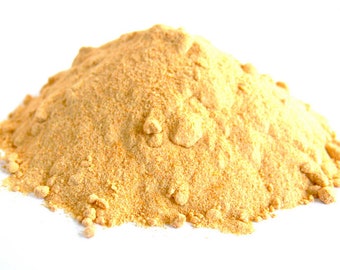 May include: A pile of yellow powder, likely a spice or seasoning, on a white background.